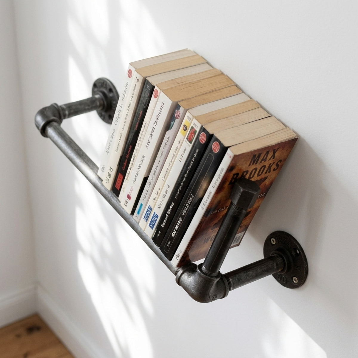 Estantería de pared de fundición fijada en una pared clara con libros de bolsillo, ambientación