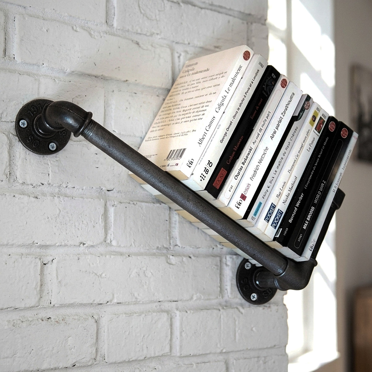 Estantería de pared de fundición sobre pared de ladrillo con libros, ambientación loft
