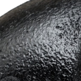 Primer plano de la pintura negra mate y granulada de un racor de fundición